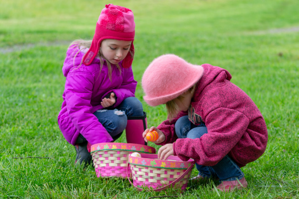 Two Children Inspecting Their Easter Eggs in Their Baskets