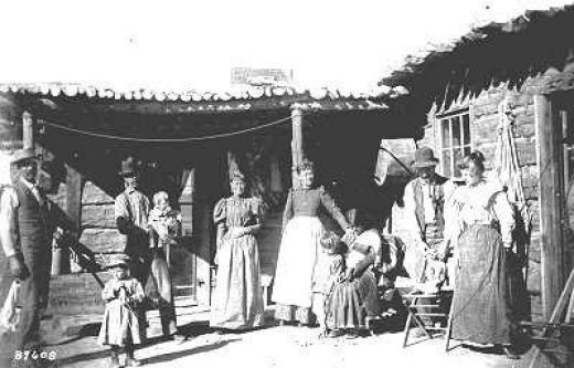 pioneer family in front of a log home