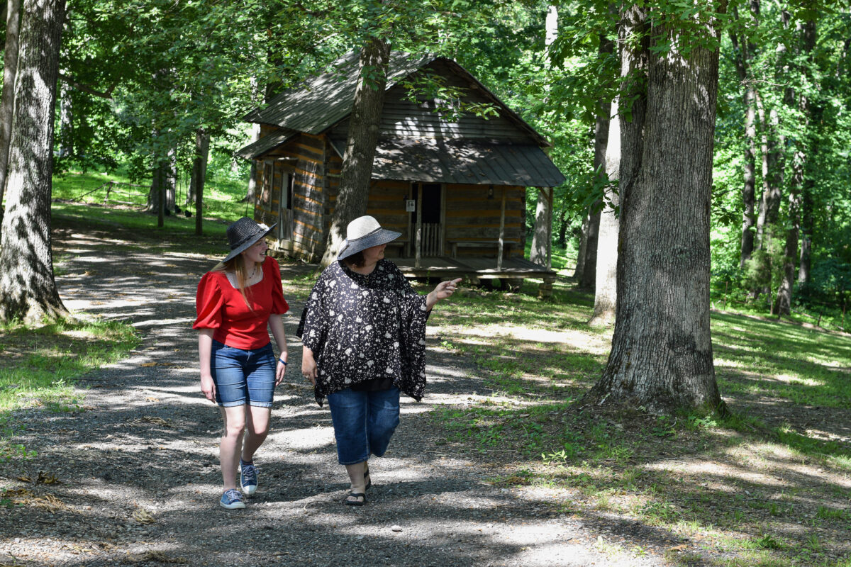 females walking on a lane by a cabin